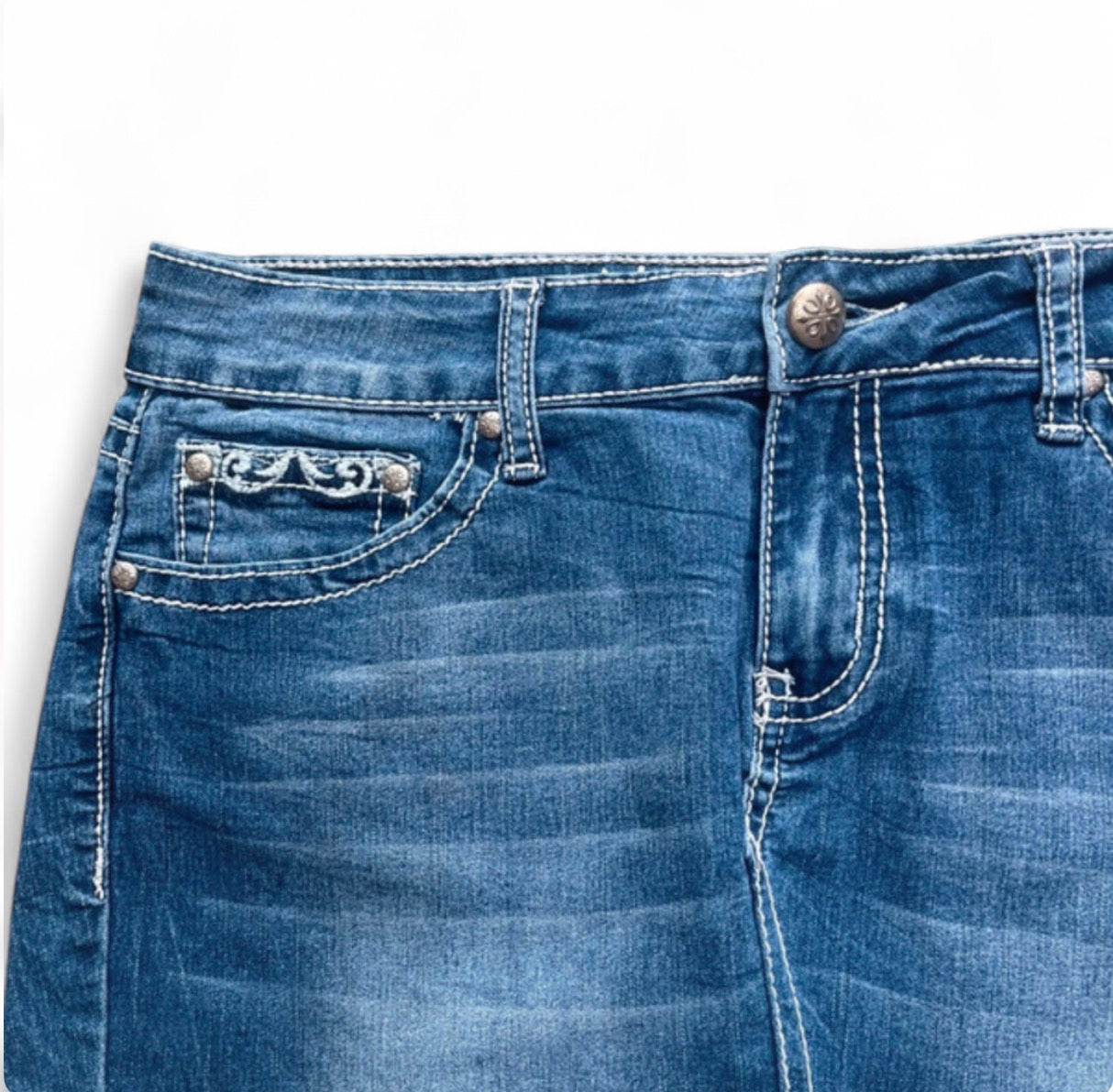 Close-up of blue jeans with decorative stitching on a white background